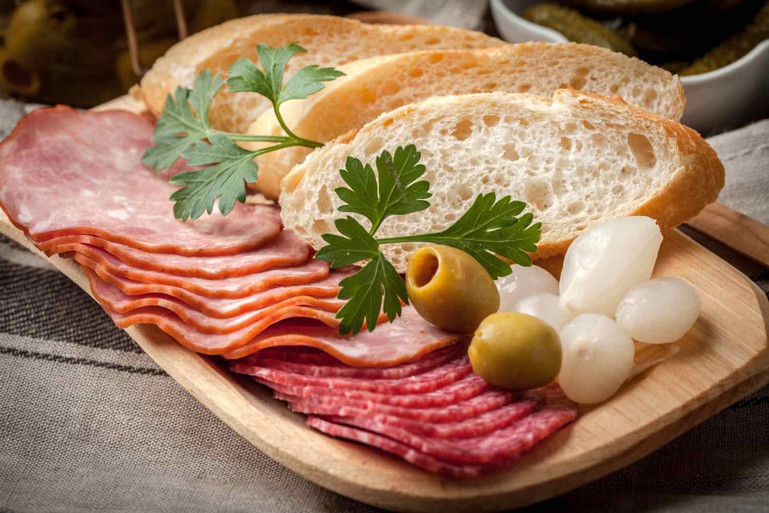 Spanish cuisine. Tapas with sliced sausage, salami, olives, marinated onions, cucumber and parsley on a wooden table.