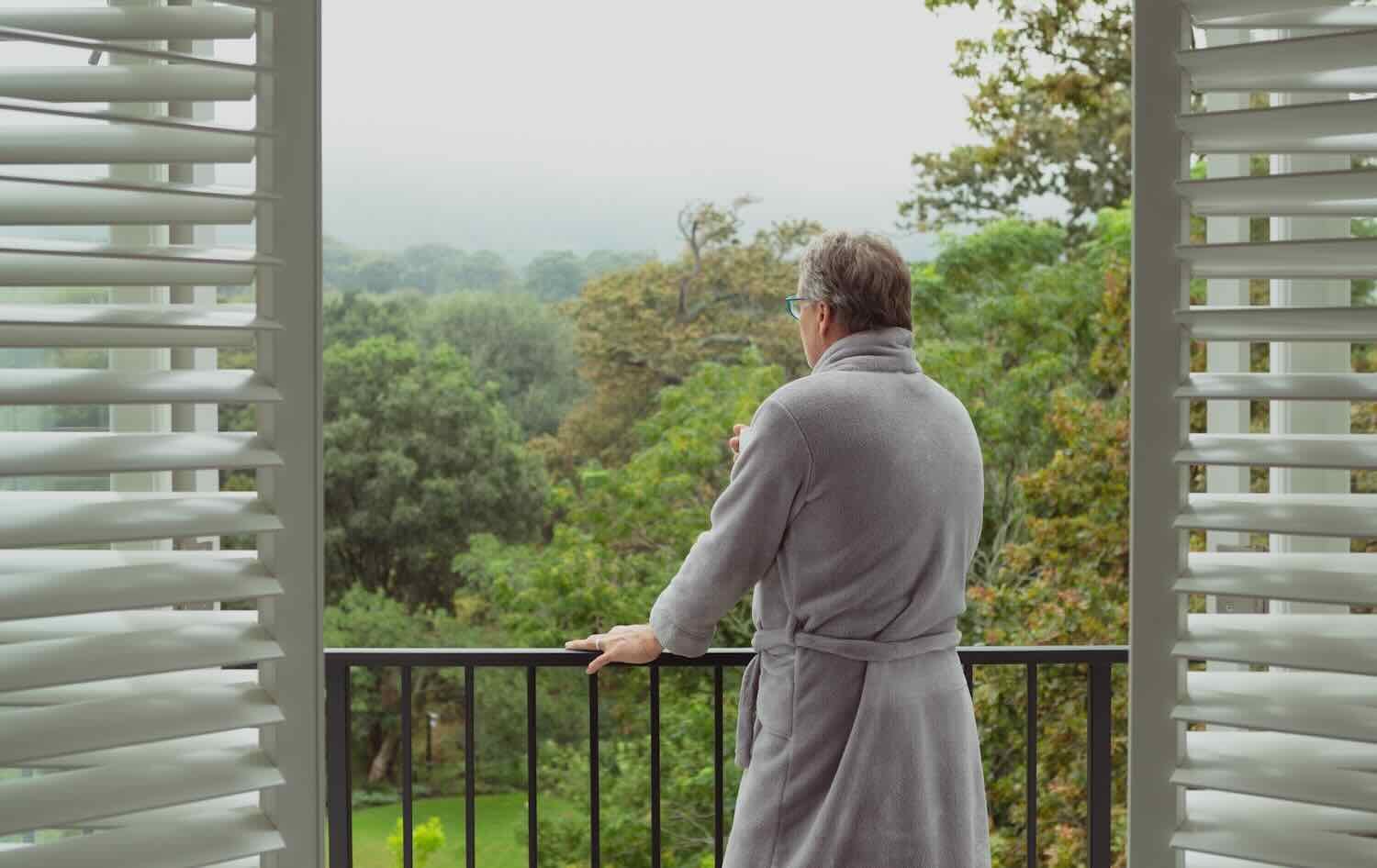 Rear view of active senior Caucasian man standing in balcony in a comfortable home